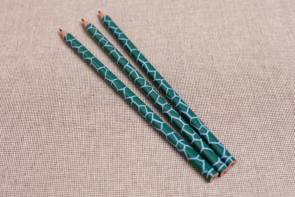 Three green pencils with a dinosaur skin design